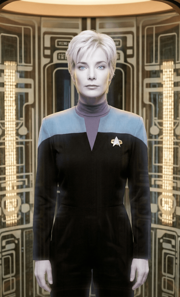 Angela Feathersone as HOLIE. The Holographic On-Line Interactive Encyclopedia, or HOLIE for short, stands at attention in her alcove on the bridge of the USS Cantabrian in 2372.